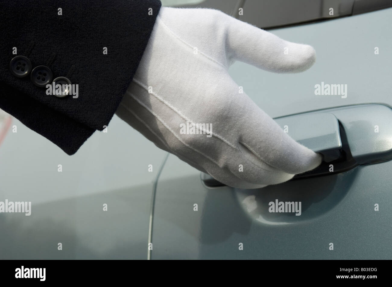 Hand wearing formal white glove opening car door. Five star luxury. Service. Stock Photo