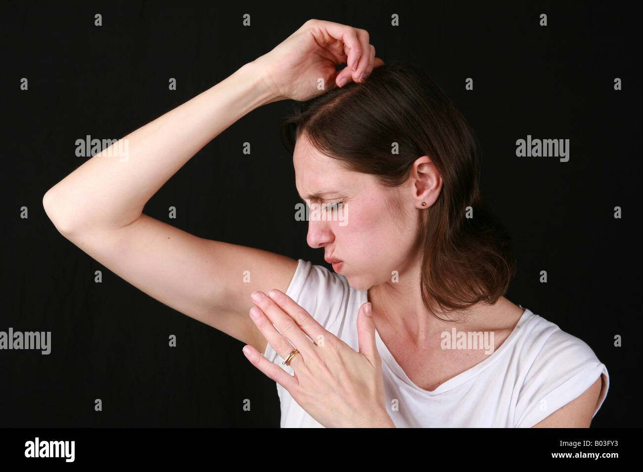 Young 20s 30s woman smells armpit with disgust at strong under arm body odour BO unwashed poor