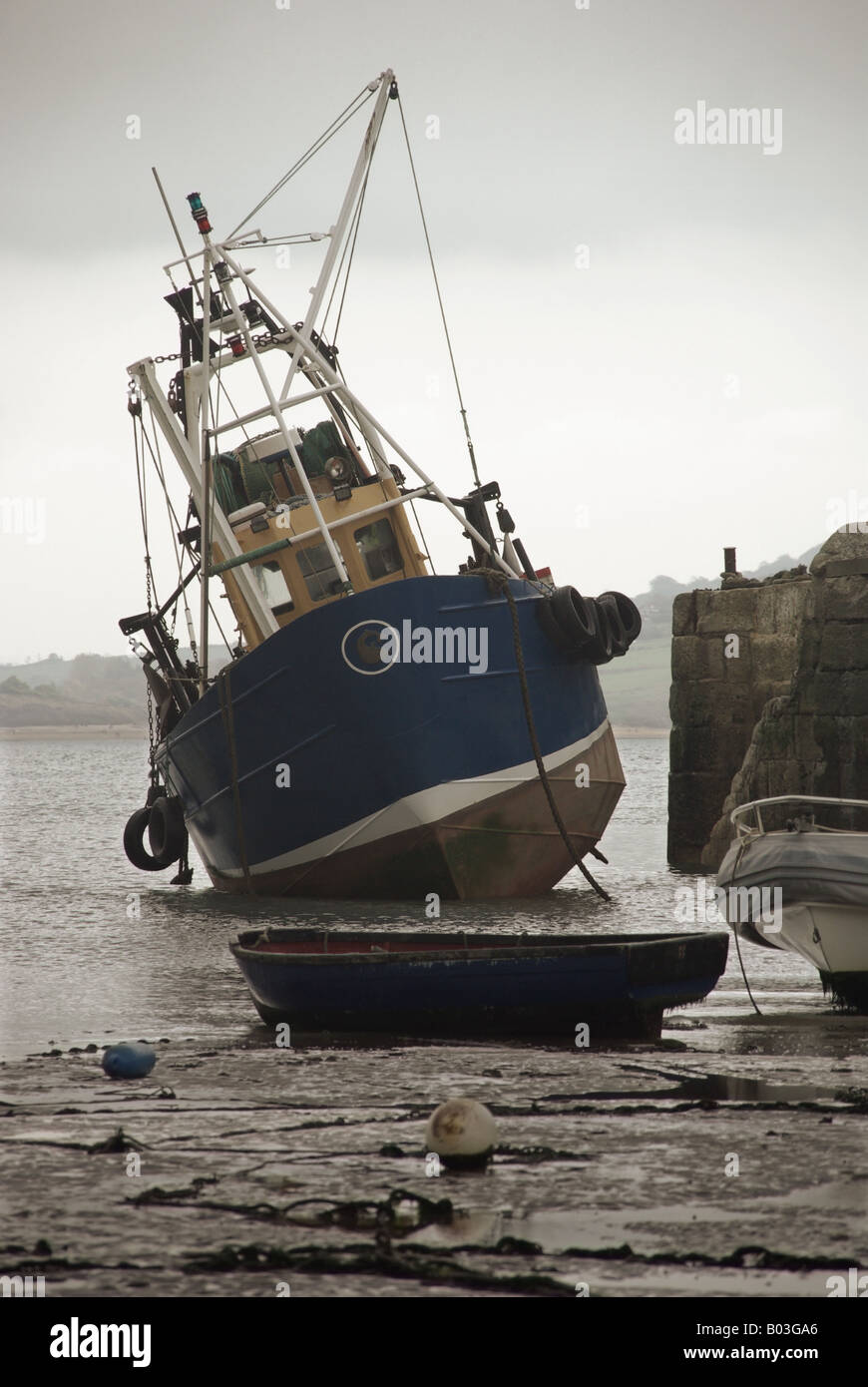 Leaning boat in harbour A small boat leans at a drunken angle grounded