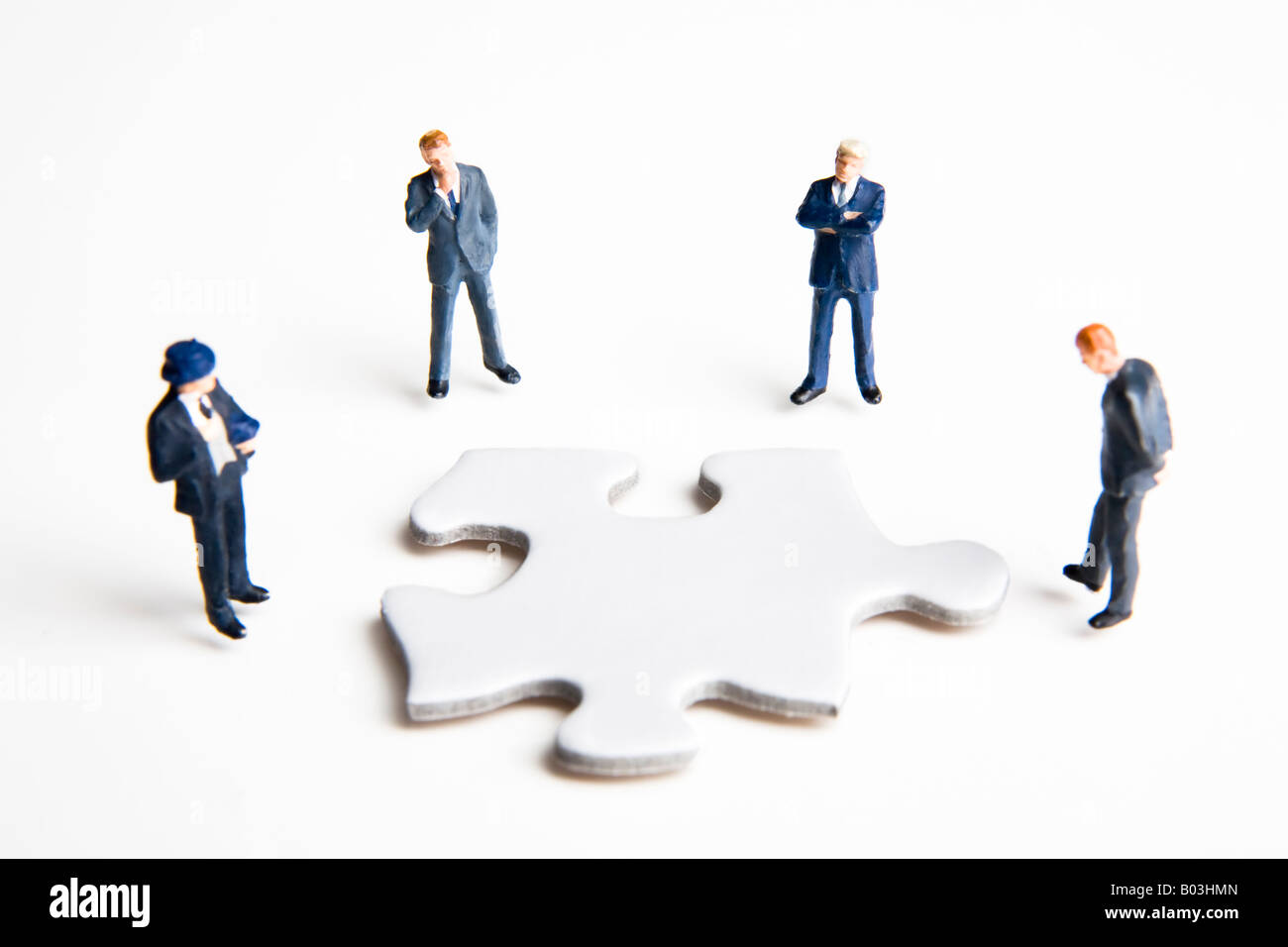 Businessmen figurines standing around a puzzle piece Stock Photo