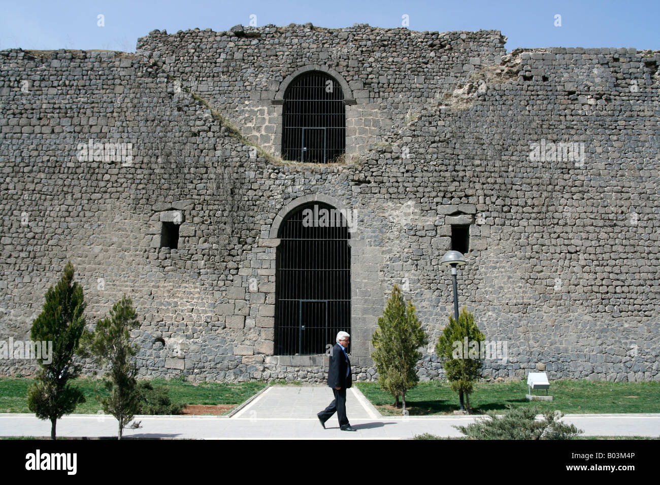 A pedestrian walks past a section of the black basalt city walls in Diyarbakir Turkey Stock Photo