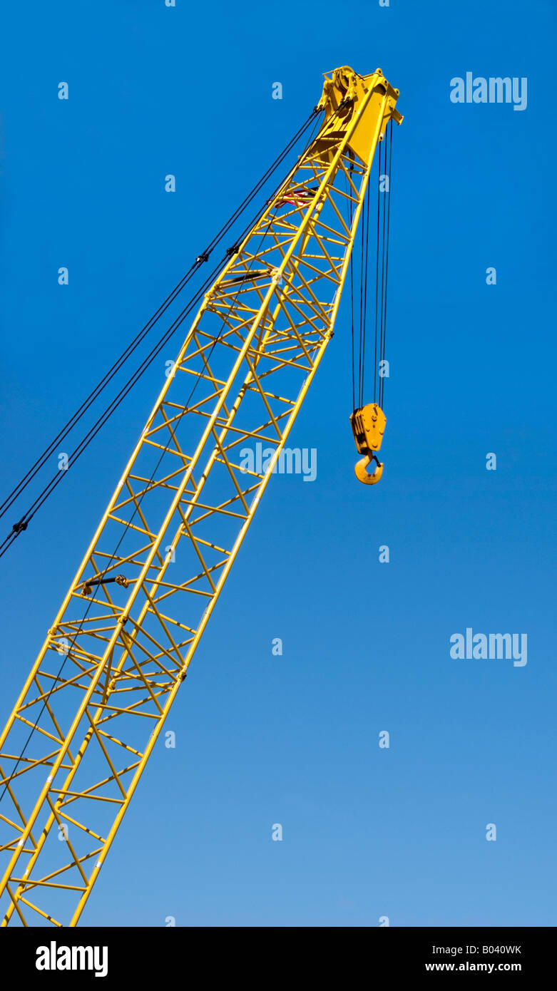 Yellow crane boom against blue sky Stock Photo