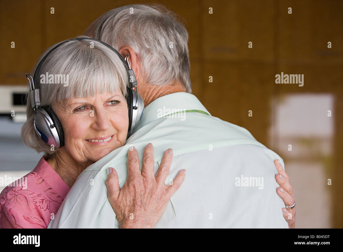 Woman with headphones hugging husband Stock Photo