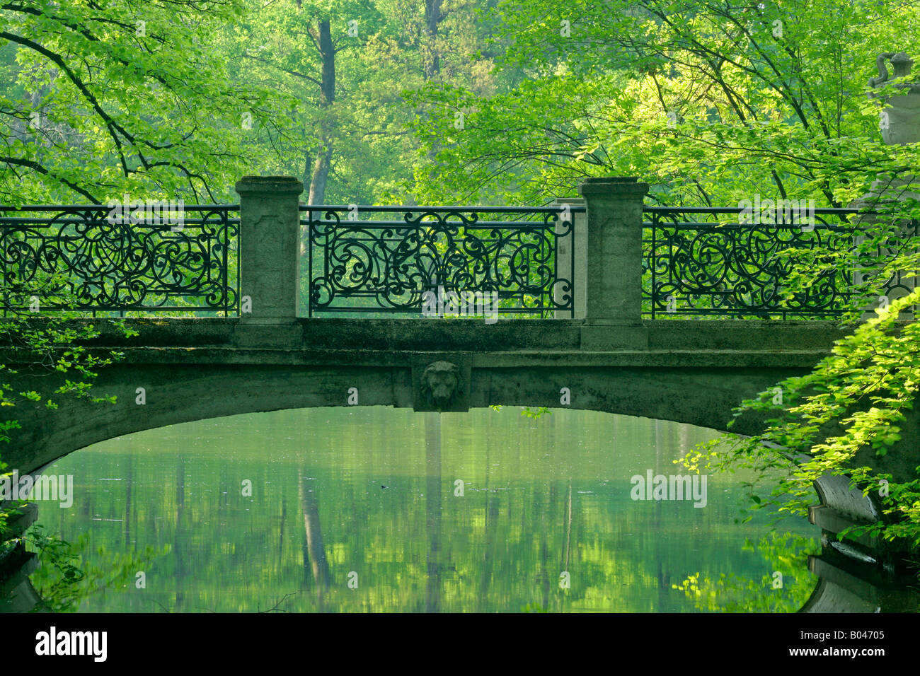 Romantic bridge in baroque style built bridge reflecting in brook in spring forest Park of Nymphenburg castle Munich Bavaria Ger Stock Photo