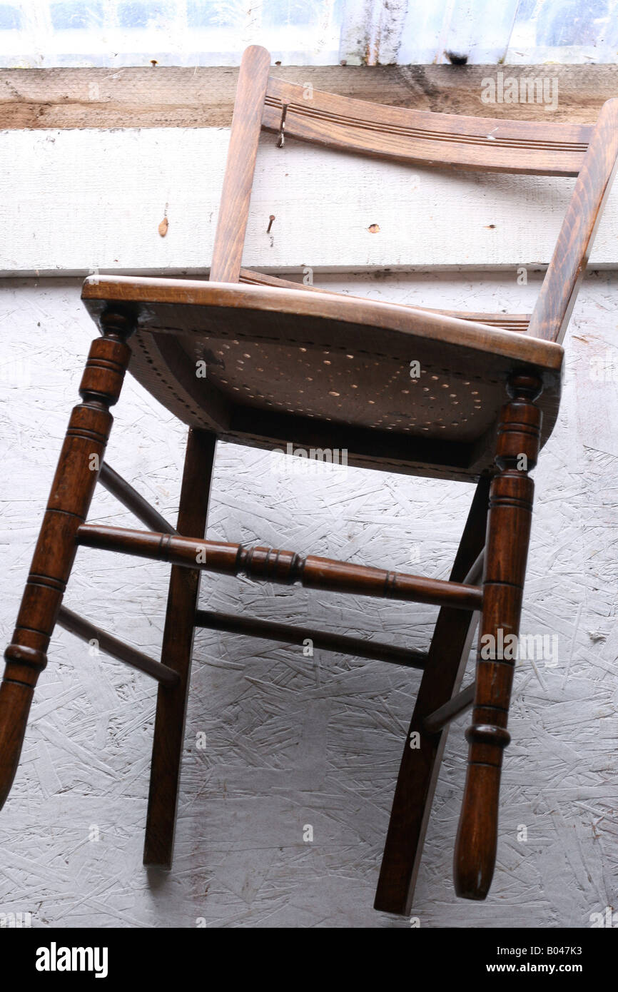 Vintage wooden chair on hook in antique shop Stock Photo