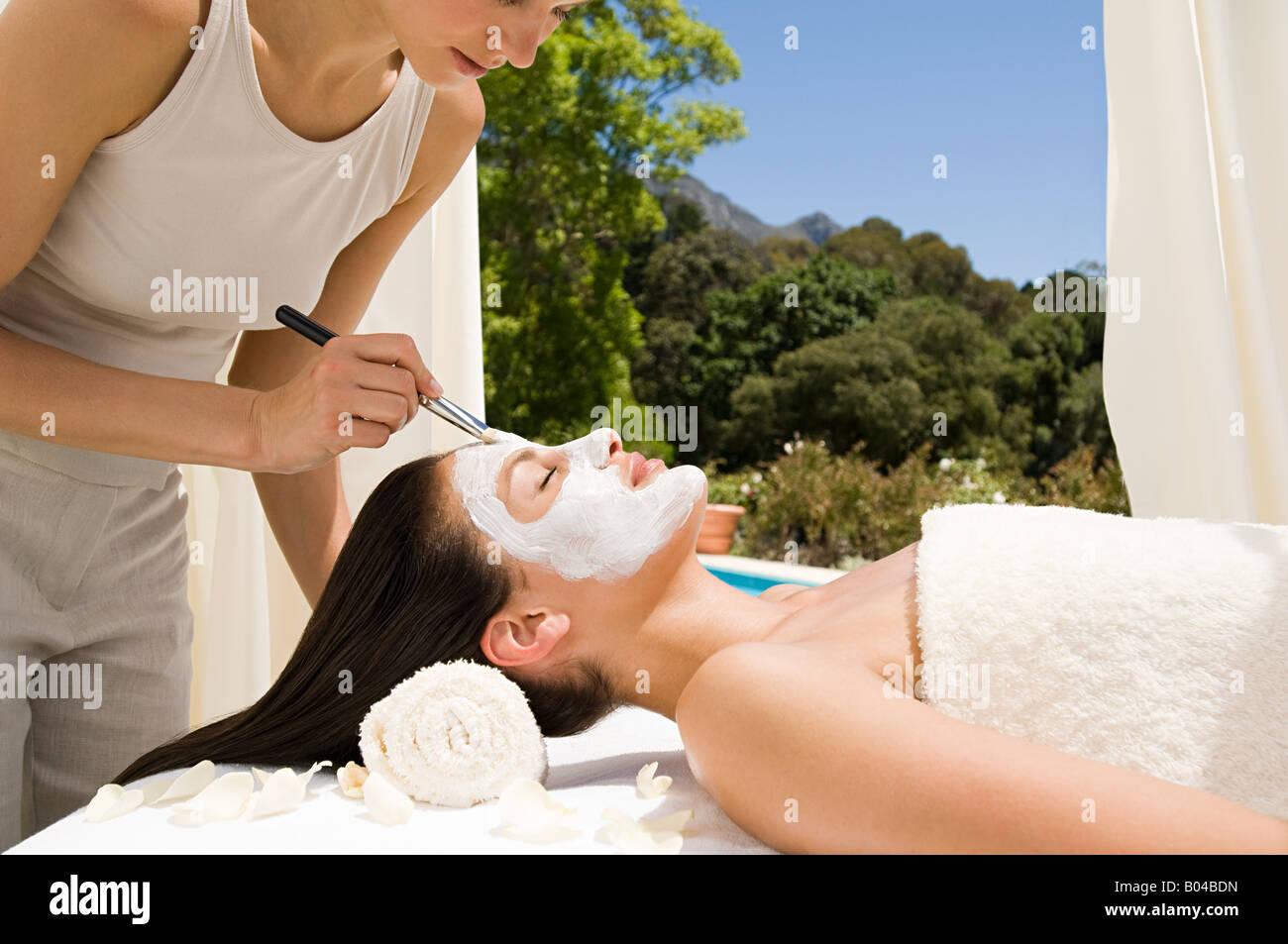 A beautician applying a face mask to a womans face Stock Photo
