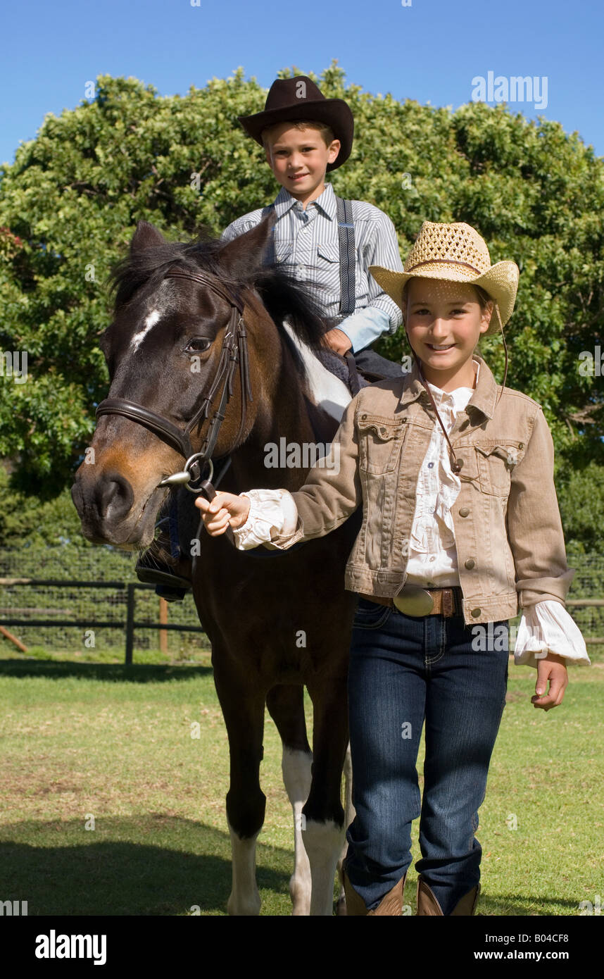 A girl walking a boy on a horse Stock Photo