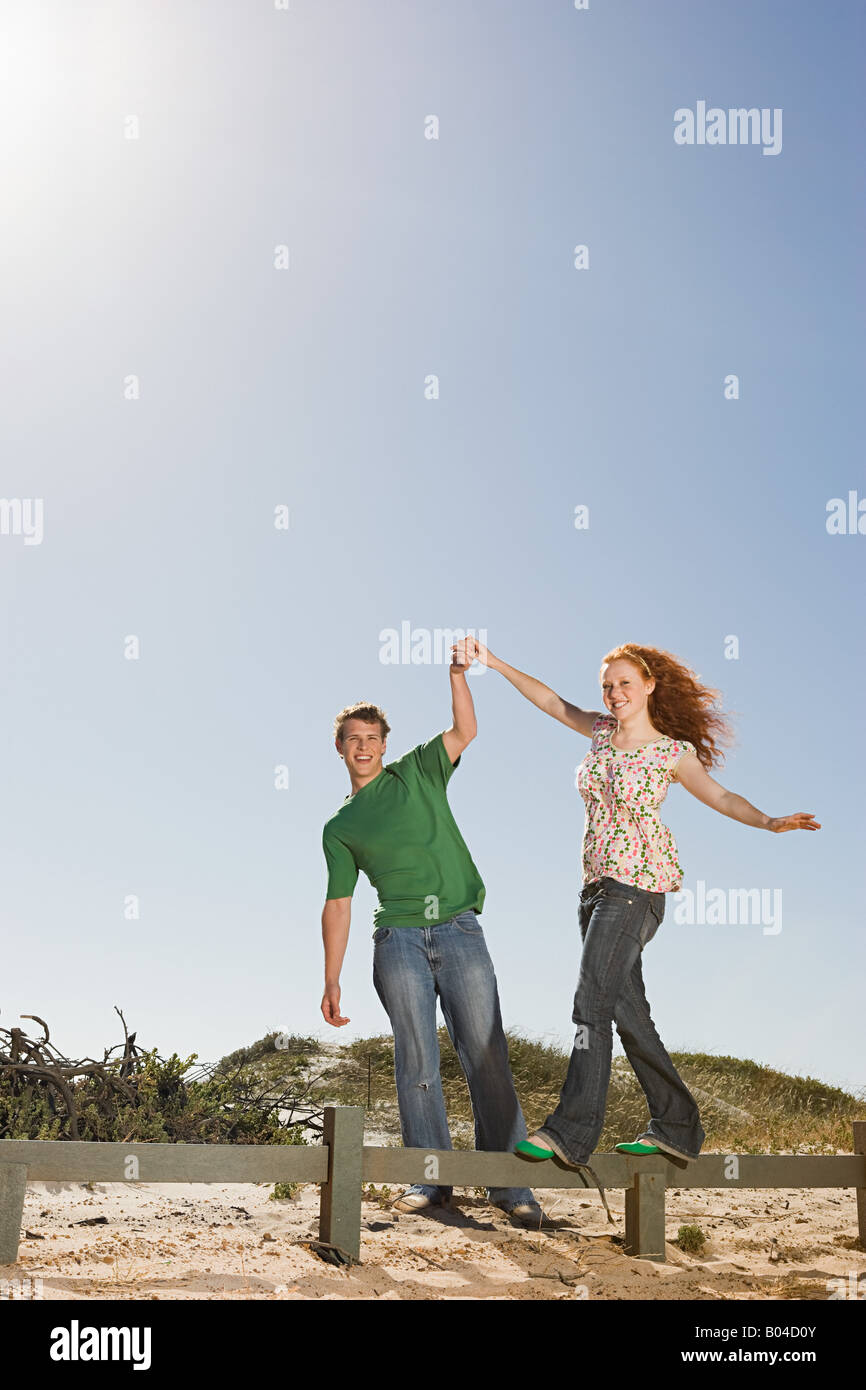 A young man helping a woman balancing on a fence Stock Photo Alamy