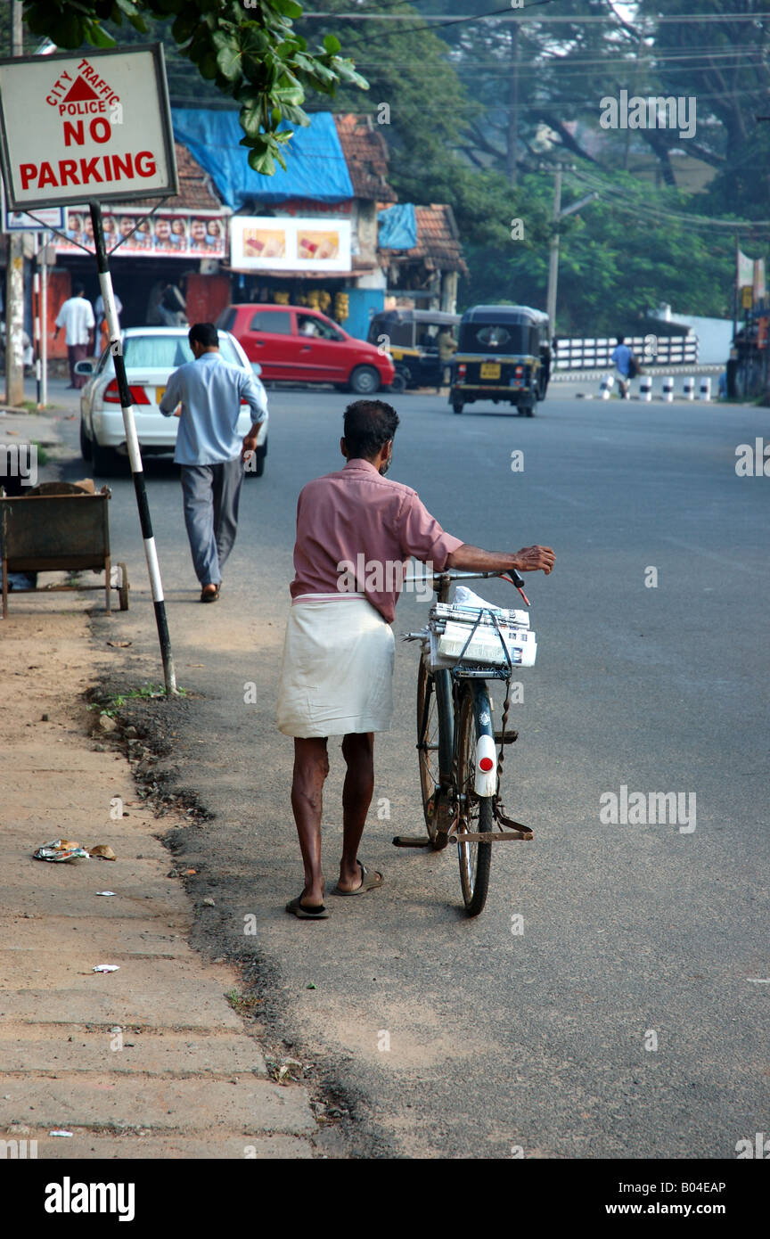 Man pushing bicycle along road in Trivandrum Thiruvananthapuram Kerala India Stock Photo
