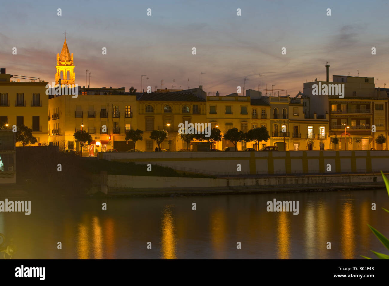 Looking across the Rio Guadalquivir (river) towards the Triana District and the bell tower of Iglesia de Santa Ana at dusk Stock Photo