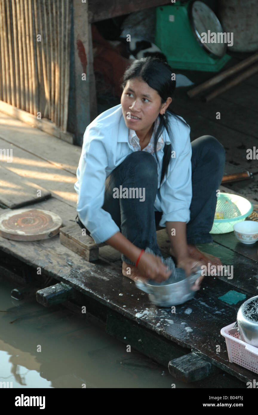 A woman from a floating village at Tonlé Sap Lake, Cambodia, uses the lake to do her family's washing up. Stock Photo