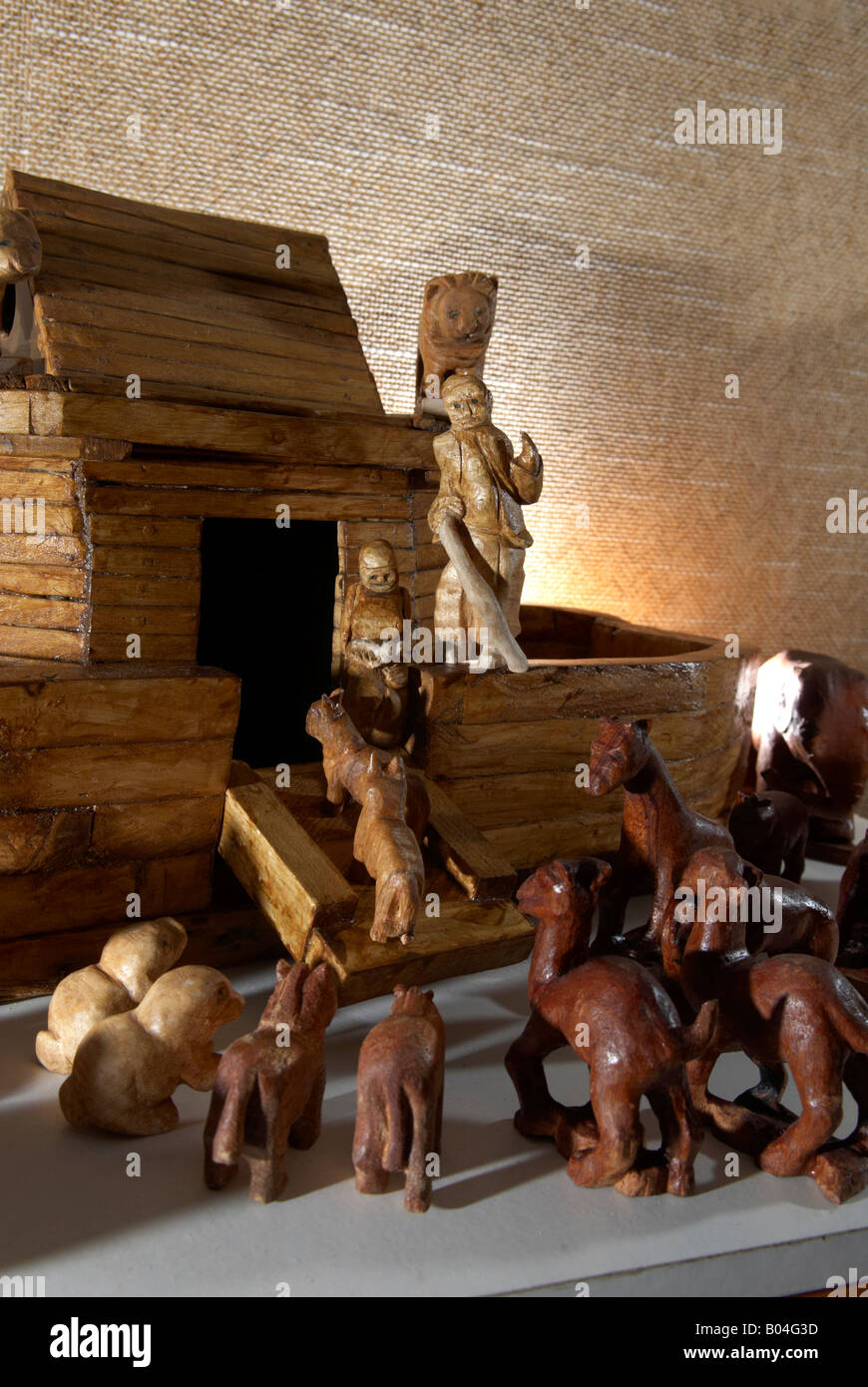 Wood carving of Noah holding a stick and his Ark back lit by a flash