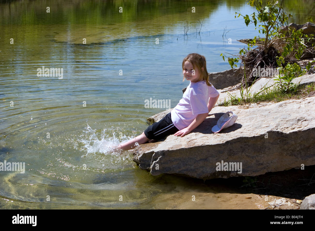Young girl splashes in river and enjoys the natural Texan landscape. Stock Photo