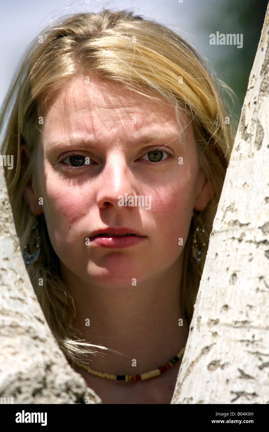 Sad girl, portrait of a beautiful young blond woman in the fork of a tree Stock Photo