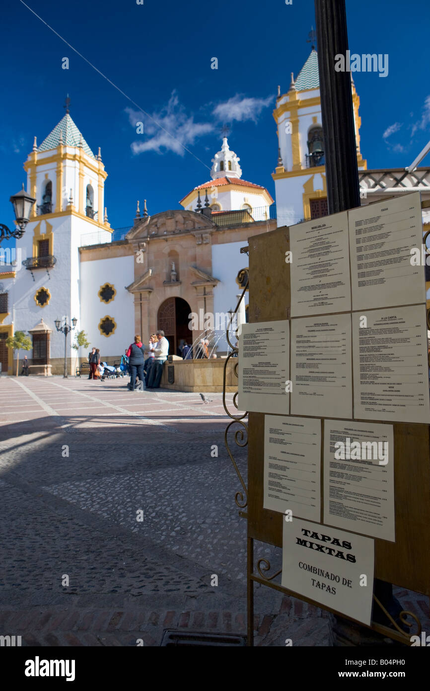 Iglesia del Socorro (church) in Plaza del Socorro and menu board of a outdoor cafe in the town of Ronda, Costa del Sol Stock Photo