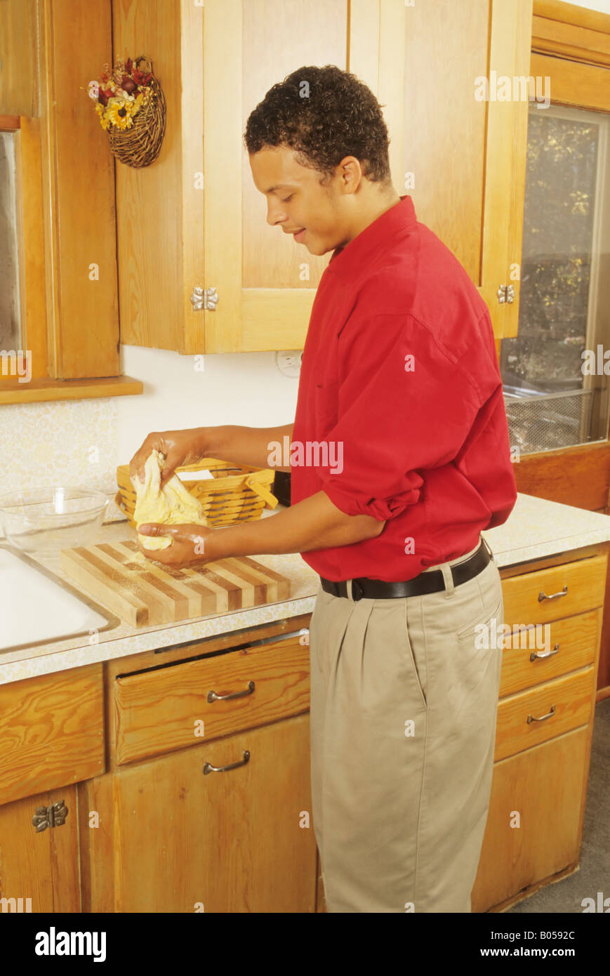 African American male teen makes bread in kitchen Ohio USA Stock Photo