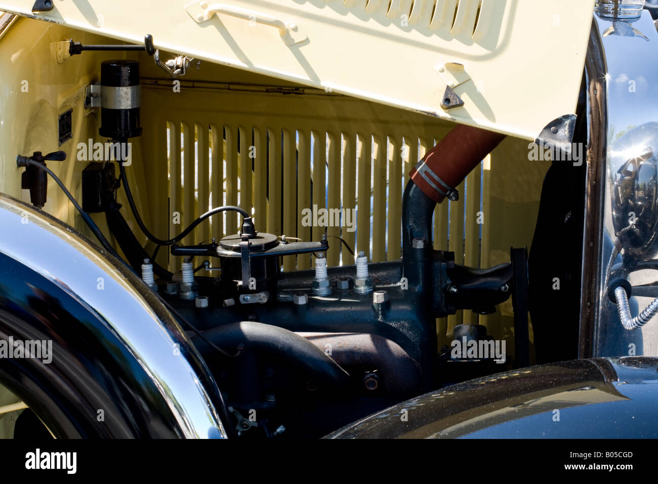Photo of a motor of a yellow model-T antique automobile behind a chrome grill with open hood at an auto show in Florida Stock Photo