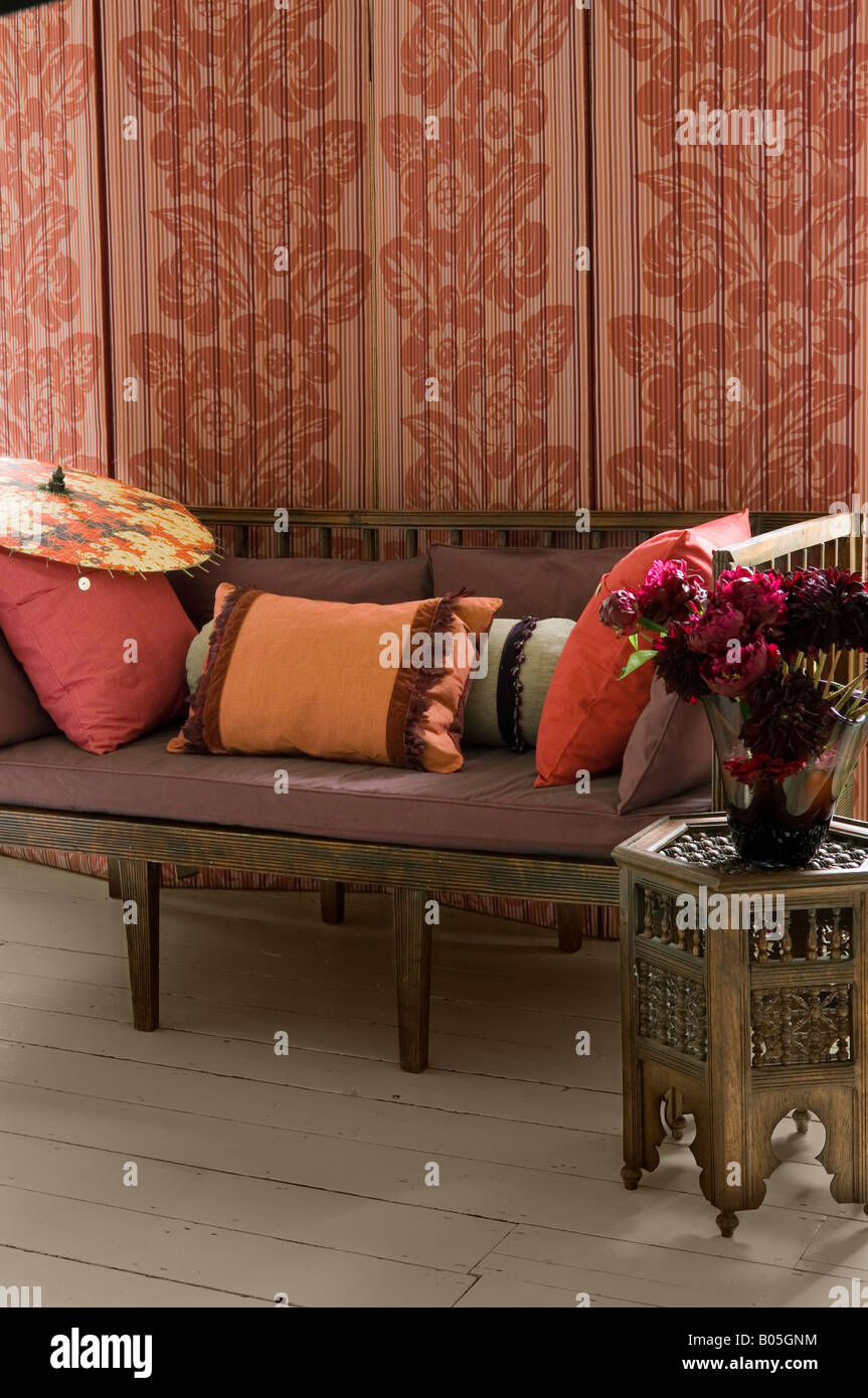 Screen with fabric by Jim Thompson behind settee with assorted cushions Stock Photo