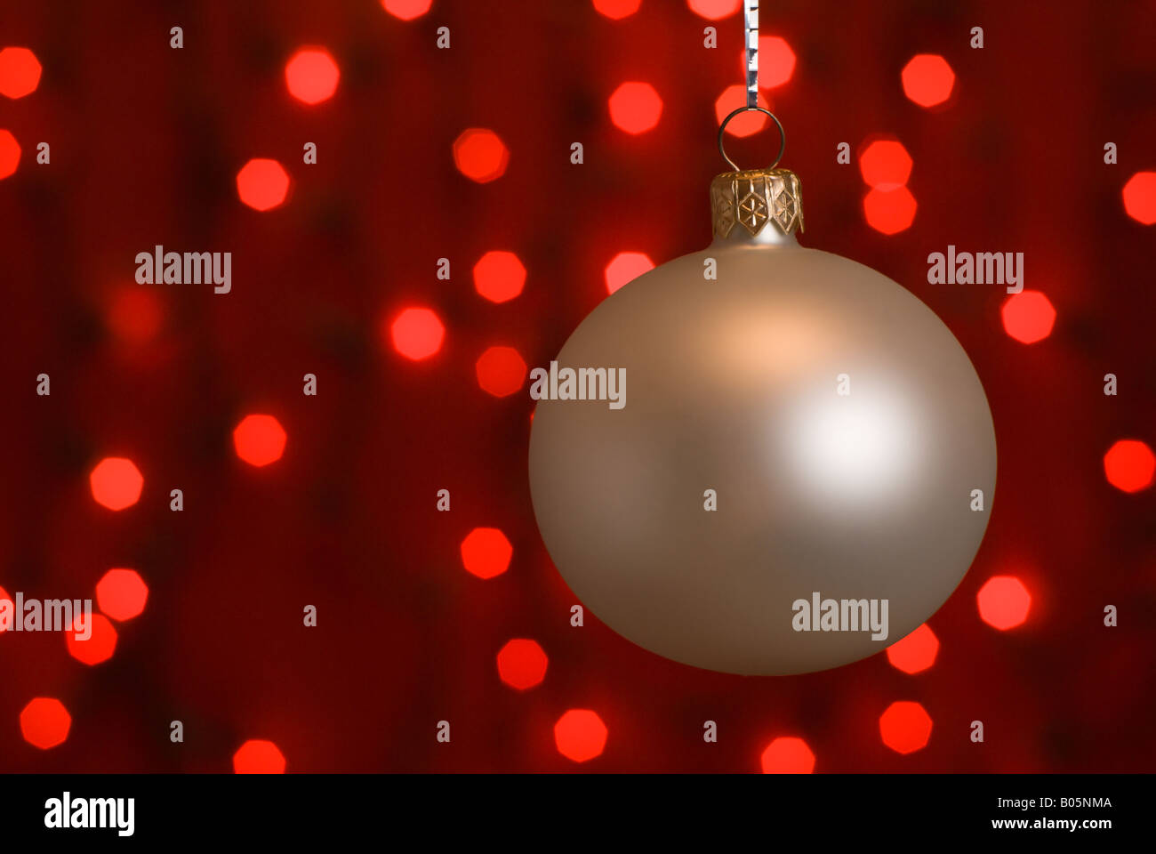 Silver christmas ball against defocused red christmas lights. Stock Photo