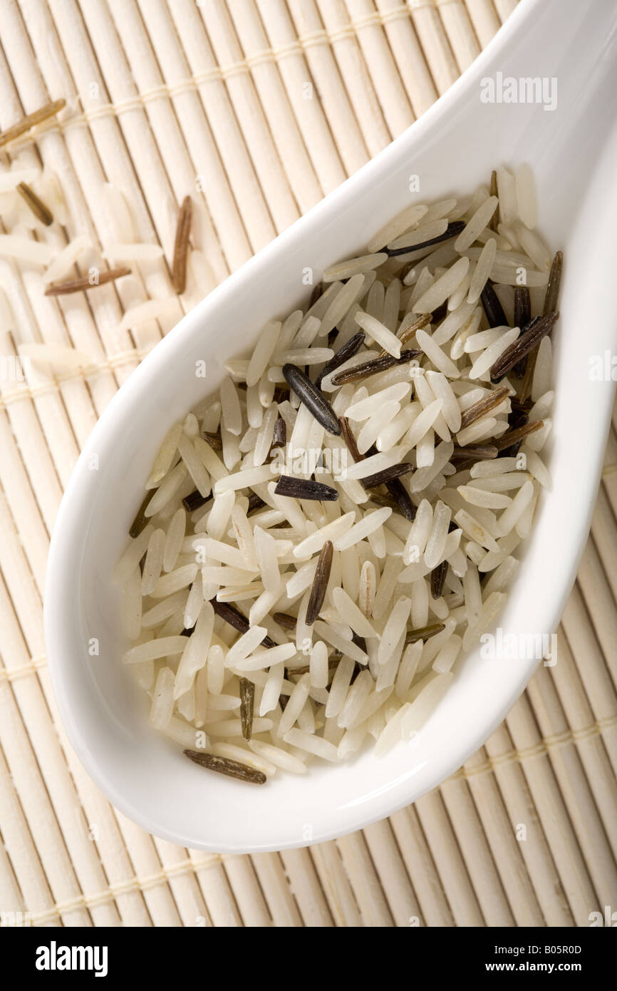 close-up on spoonful of raw wild rice with straw placemat in background Stock Photo