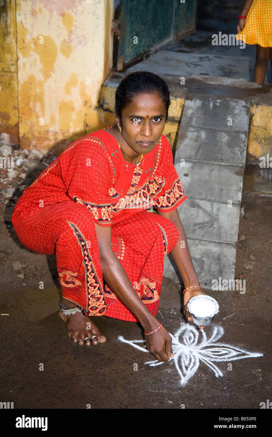 Woman making a Kolam design outside her house before nightfall, Madurai, Tamil Nadu, India Stock Photo