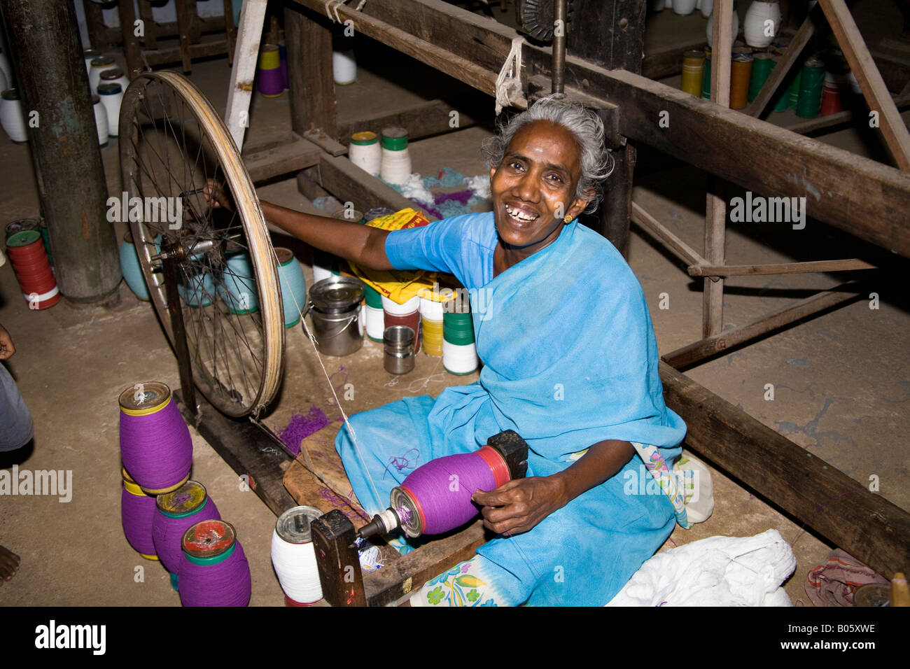 Woman working at Gandhi type spinning wheel in a weaving factory, Madurai, Tamil Nadu, India Stock Photo