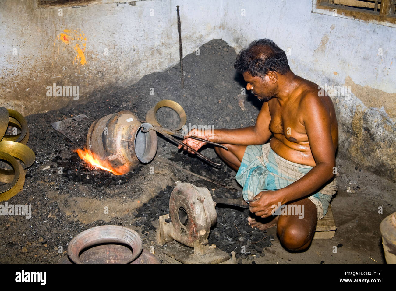 Man heating metal pot during manufacturing process, Madurai, Tamil Nadu