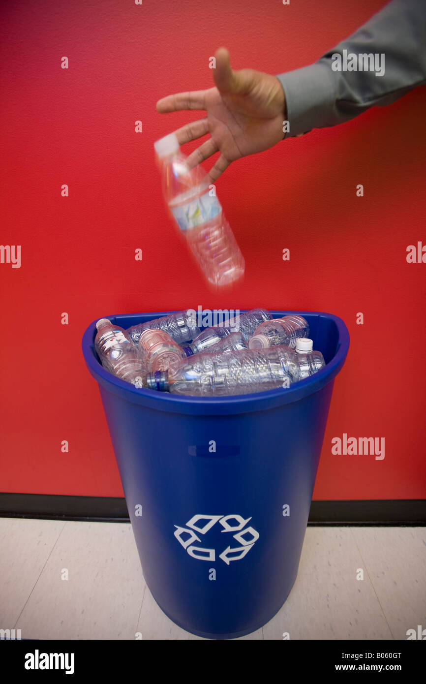Office employee dropping plastic bottle into recycling container Stock Photo