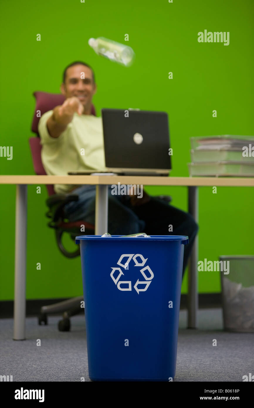Office employee throws plastic bottle into recycling container Stock