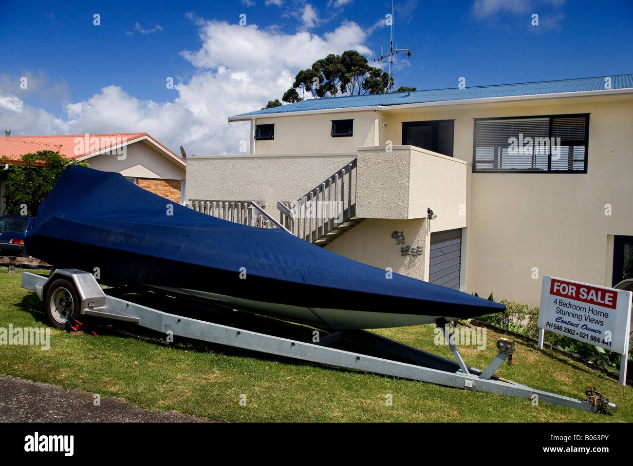 Covered dinghy in front of a modern house for sale, New Zealand North