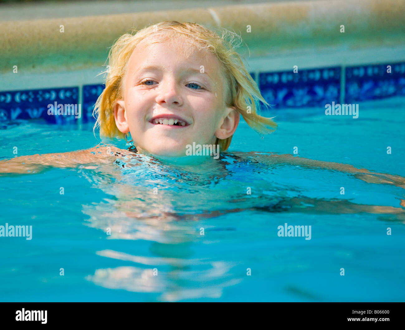 Young Caucasian girl swimming in a pool on a sunny day. Stock Photo