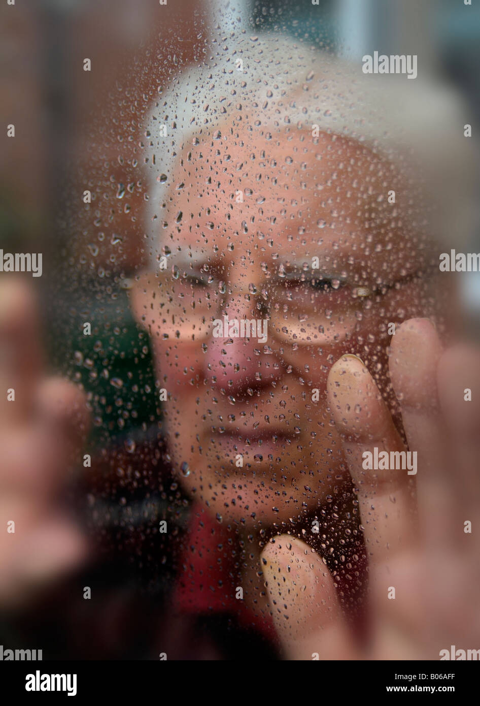 Lonely Old Man Peering Through Rain Speckled Window Stock Photo