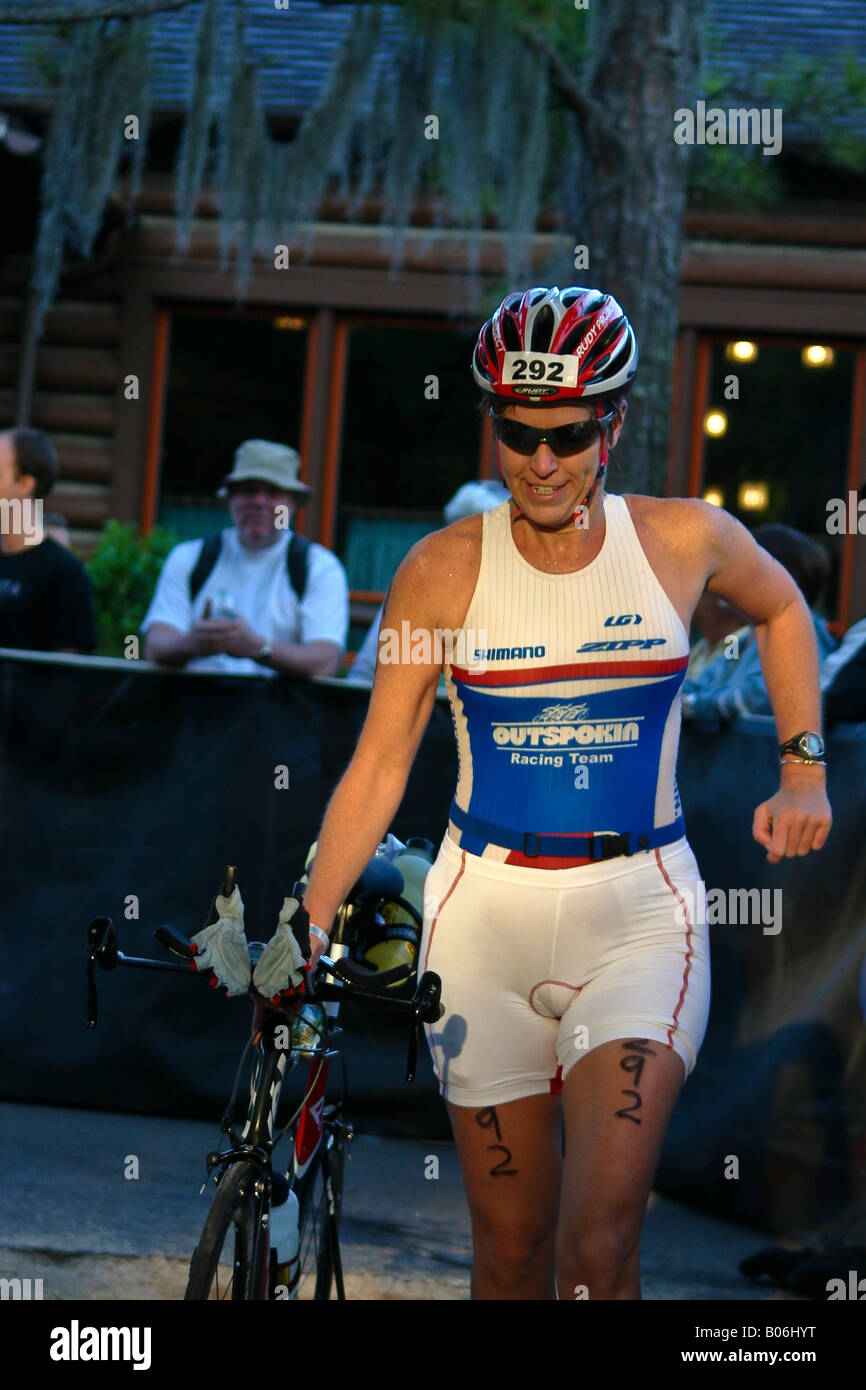 Female Triathlon Athlete Running with her Bicycle at the Disney 70.3 Mile Ironman in Orlando