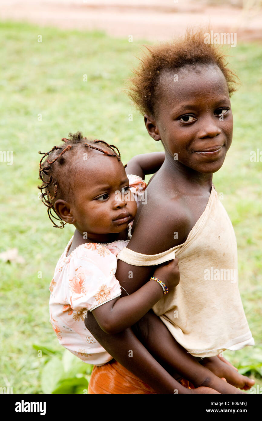 Young Gambian African girl carrying her baby sister piggy-back style Stock Photo