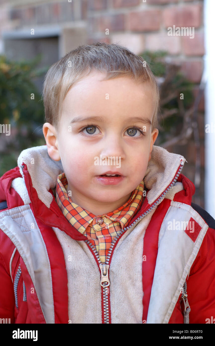 3 year old boy in red and white jacket looks at viewer full view Stock Photo