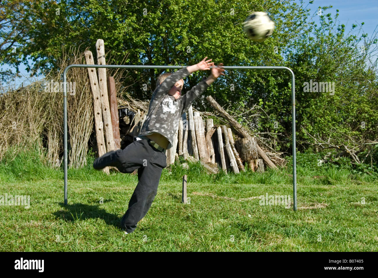 Stock photo of an eight year old boy playing football in his garden The