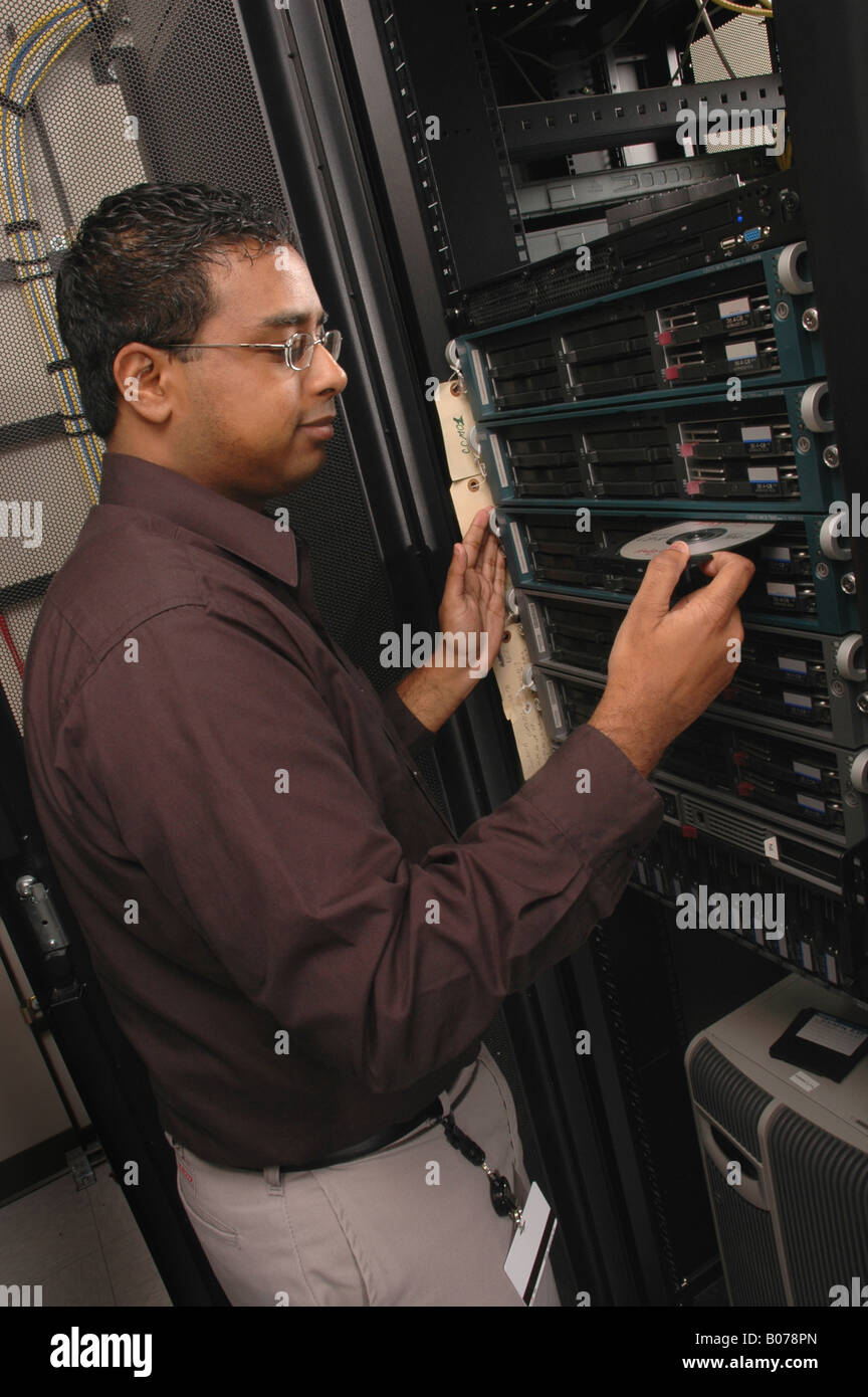 Computer technician running a backup disk for maintenance on a digital network server system Stock Photo