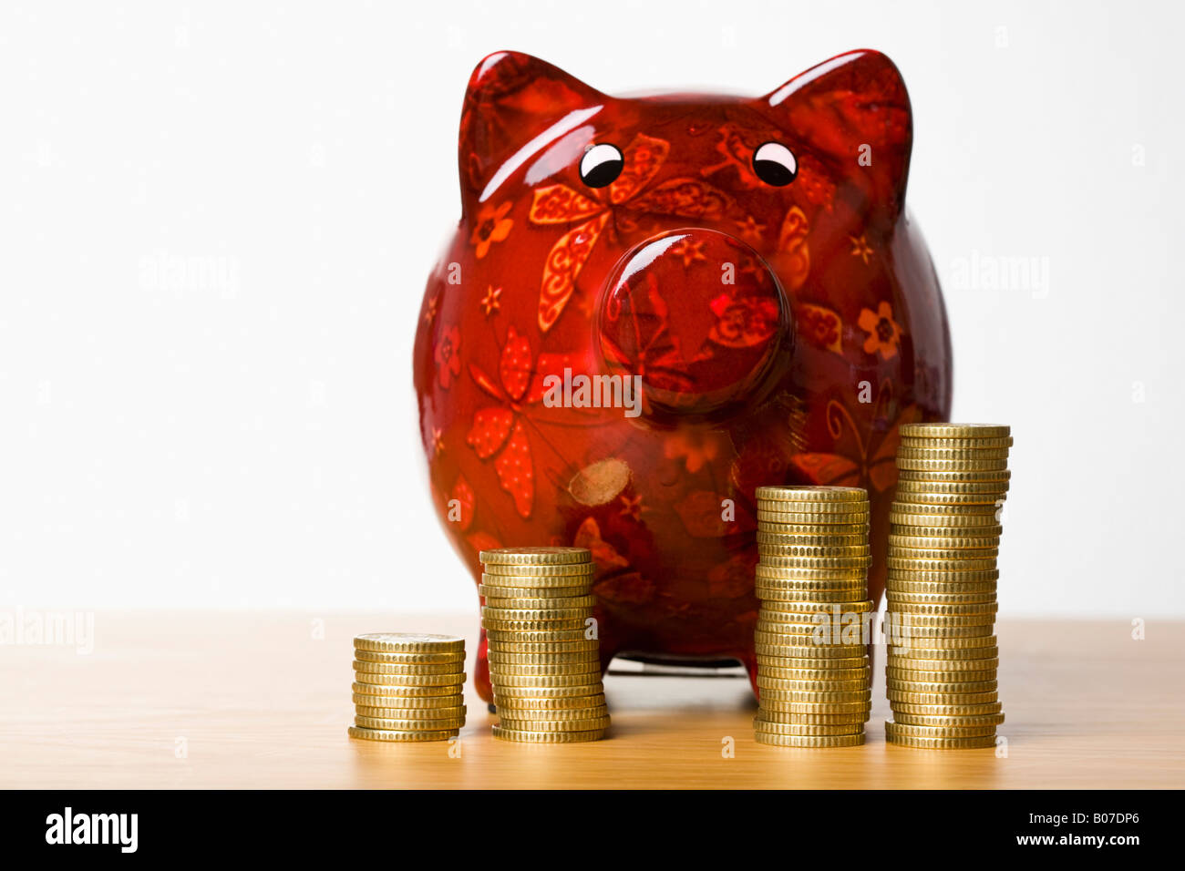 Stacks of coins in front of a piggy bank Stock Photo - Alamy
