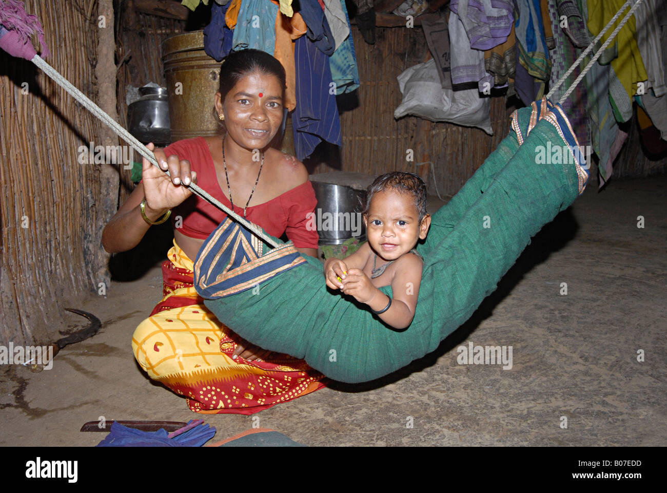 Mother swinging her baby in a hammock. Katkari tribe Stock Photo