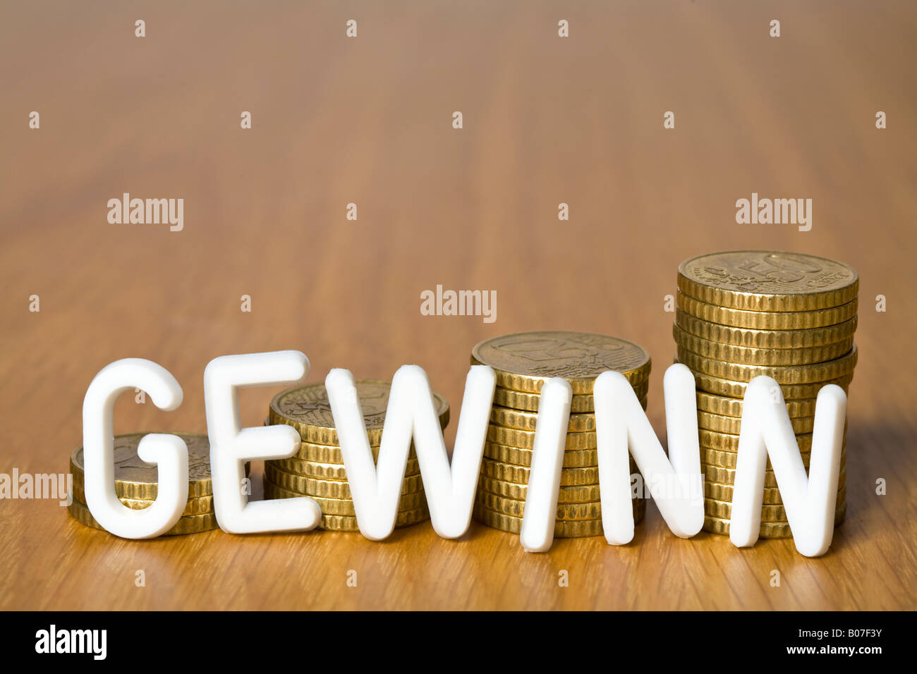 Plastic letters in front of stacks of coins Stock Photo