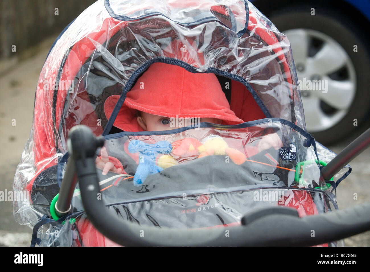 Baby in pushchair with rain cover Stock Photo