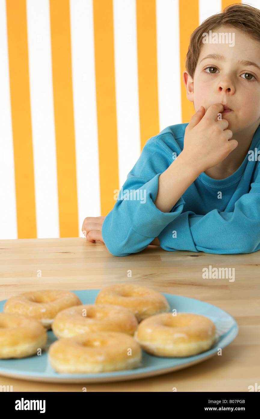 Boy sitting in front of a few donuts Stock Photo Alamy