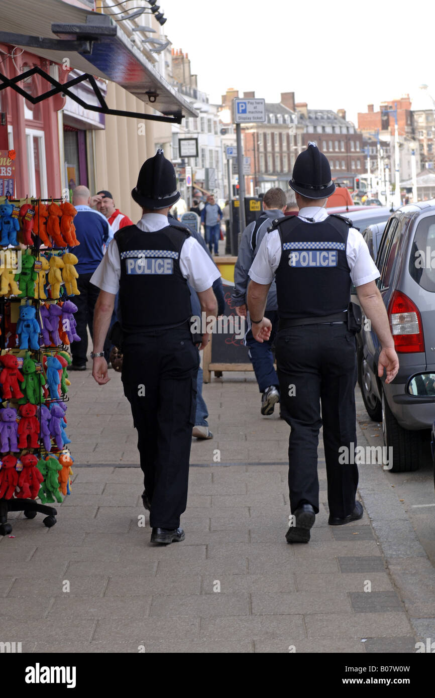 Rear view of two British Police officers patrolling the streets of ...