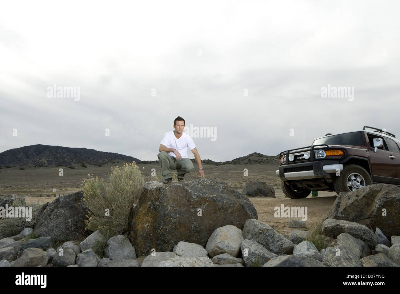 Man kneeling on rock on off-road area Stock Photo - Alamy