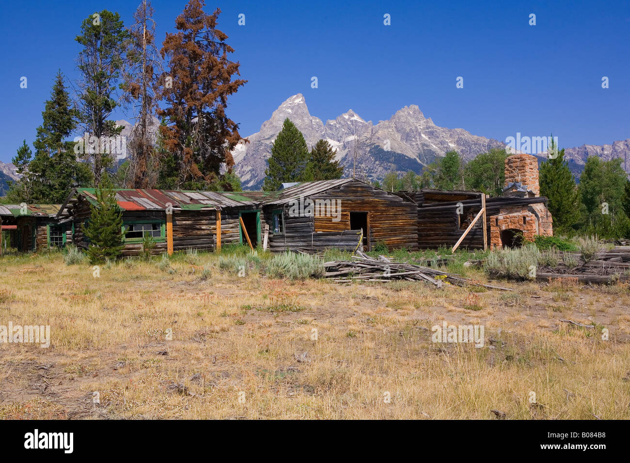 Image of an abandoned ranch house in disrepair with piles of old lumber and damaged roofing materials laying about Stock Photo