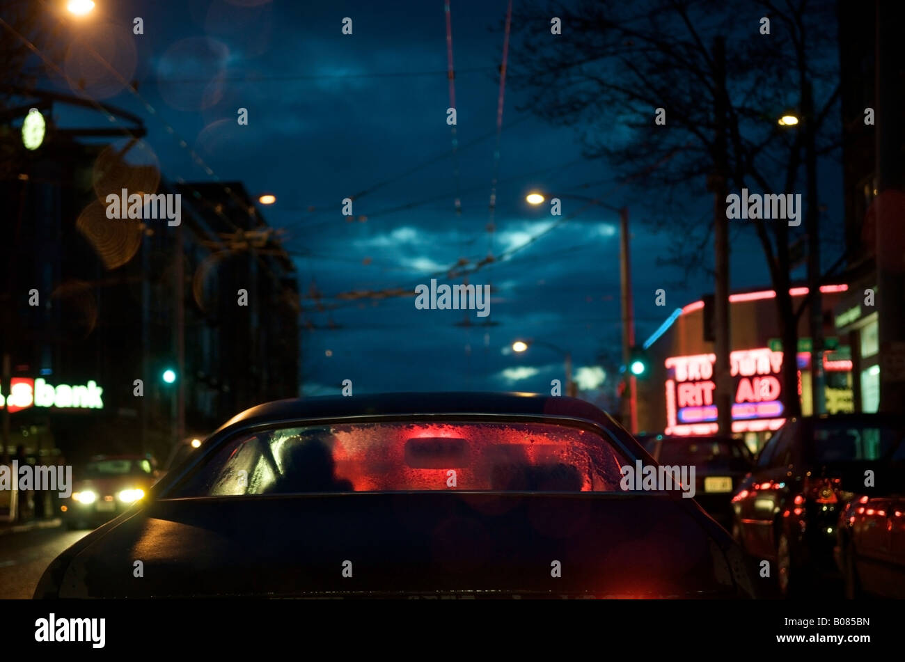 View of red brake lights through the rear window of a car on a rainy evening in Seattle, WA, USA. Stock Photo