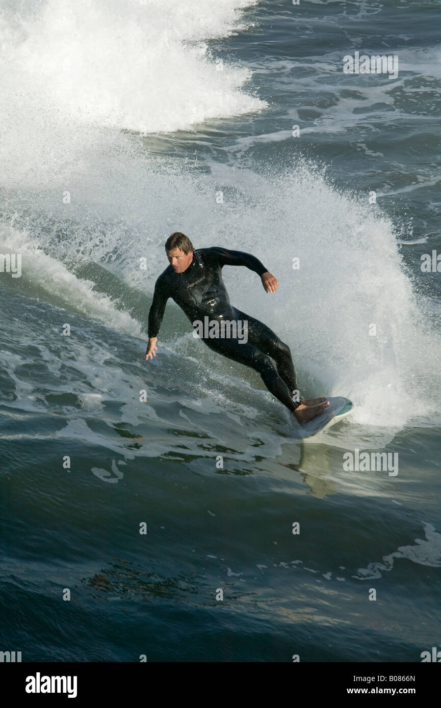 A surfer in a wet suit leans into his turn in the Pacific Ocean Stock Photo