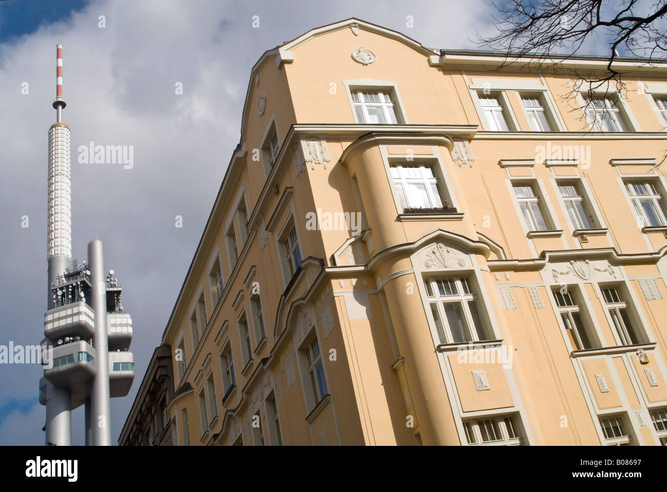 Horizontal view of the uber modern Zizkov Television Tower side by side an old baroque style apartment block on a sunny day. Stock Photo