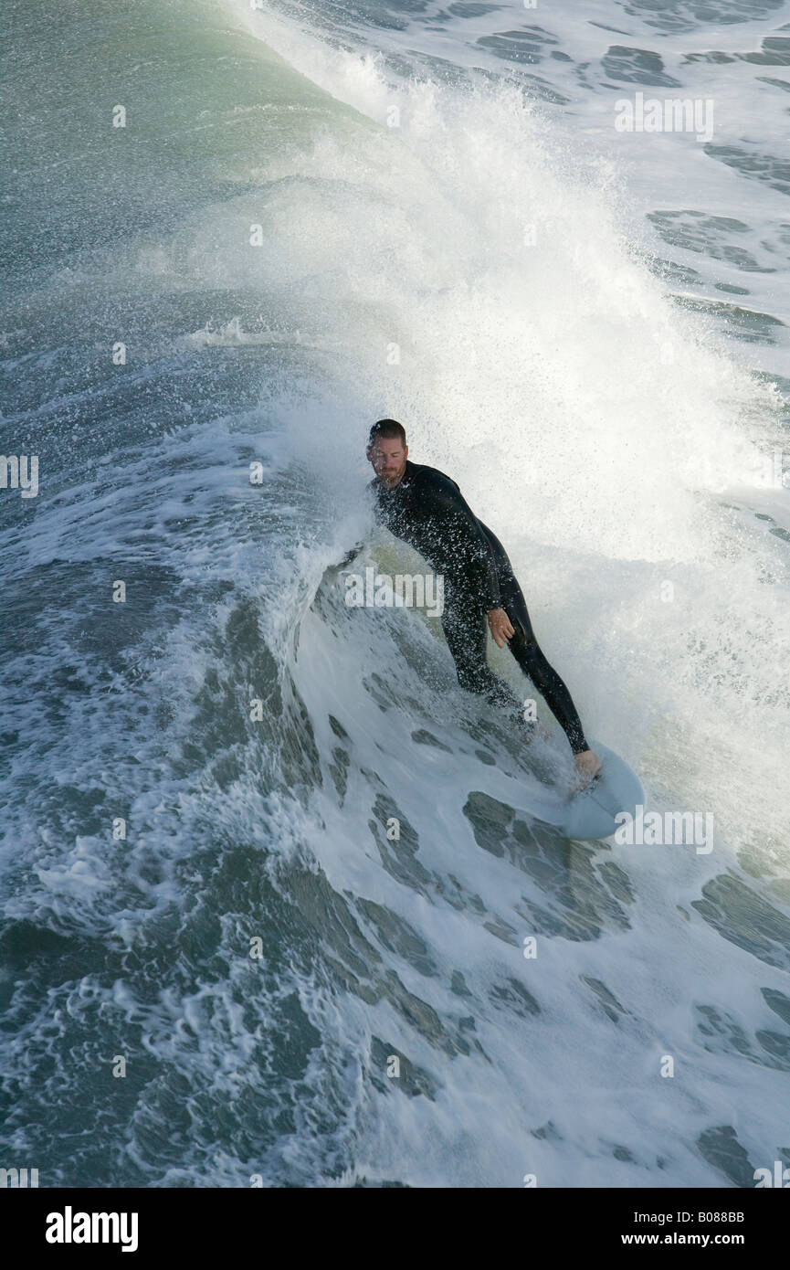 A surfer rides his surfboard along the edge of a breaking wave. Stock Photo