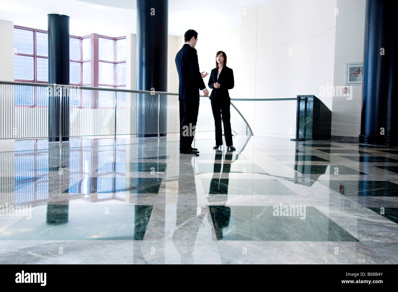Businessman and woman having discussion in lobby Stock Photo - Alamy